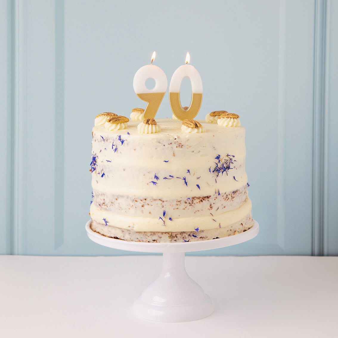 Gold &amp; White Number Candle by talking tables at penny black - 90 on top of a naked cake on a cake stand.