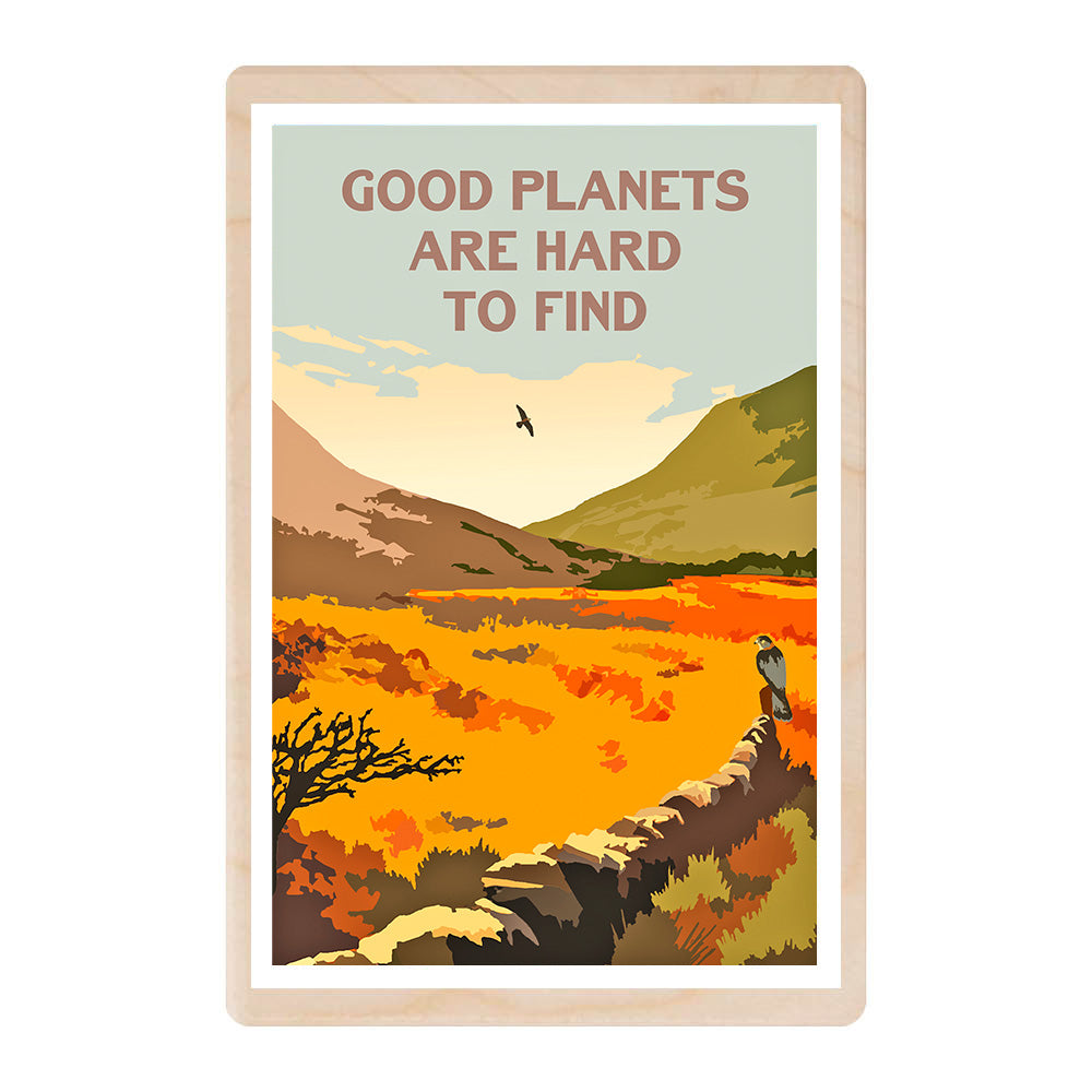A wooden postcard with a digitally illustrated scene of 2 mountains in a glen with a stone dyke wall. A buzzard sits on the wall and there are capital letters in the sky of the scene stating GOOD PLANETS ARE HARD TO FIND.