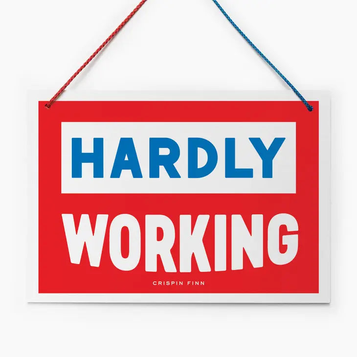 An image of a red hanging sign with a vintage feel. It has the words &#39;hardly working&#39; in block capitals and a half red/half blue hanging cord.