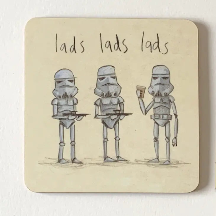 A drinks coaster with a cream background showing 3 white stormtroopers and the words &#39;lads lads lads&#39; handwritten above them. Two stormtroopers are holding black guns and pointing them at the third who is holding a drink.