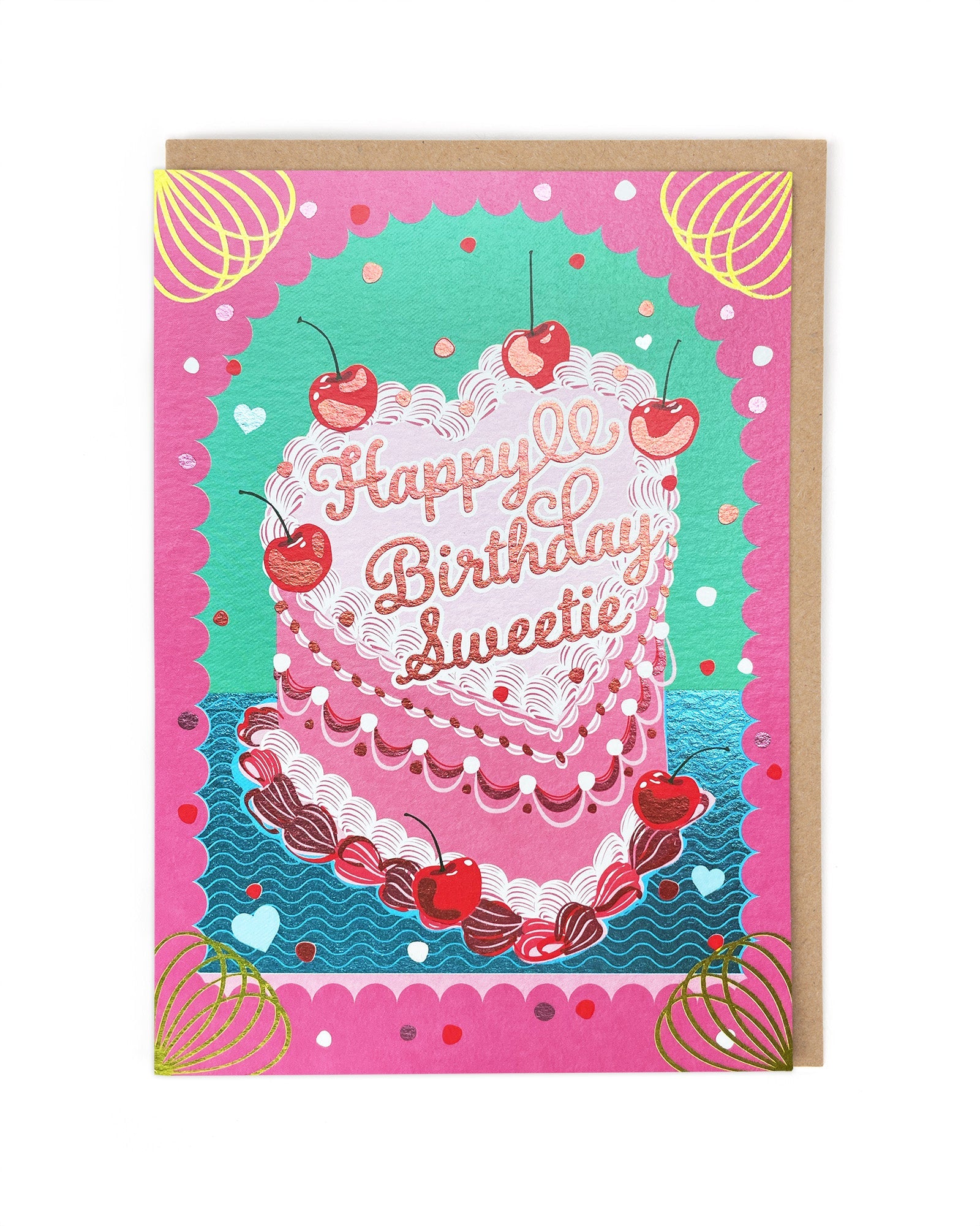 A shiny greetings card with a heart shaped birthday cake in the middle that is highly decorated with icing and cherries. It sits in a cerise pink arch with gold accents and the words on the cake read 'happy birthday sweetie'.