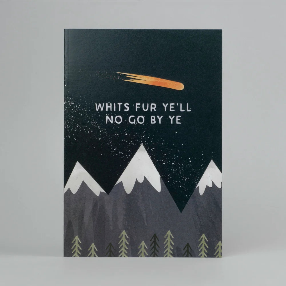 A dark coloured notebook with a Scots language saying 'Whit's Fur Ye'll No Go By Ye' in the centre surrounded by a mountainous scene and shooting comet overhead.