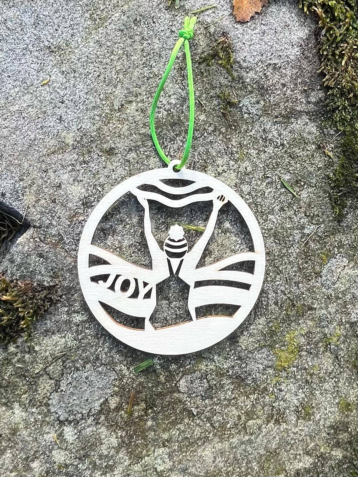 Wild Swimming Wooden Hanging Decoration by penny black, shown on a beach