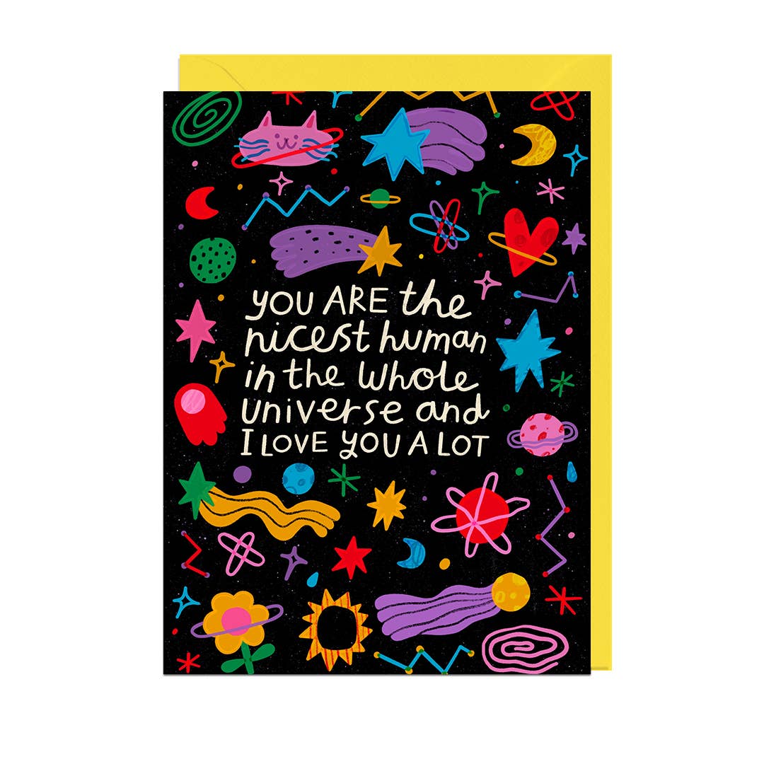 A black greeting card with a colourful space-themed doodle pattern and the text 'you ARE the nicest human in the whole Universe and I LOVE YOU A LOT', shown with a yellow envelope behind it on a white background.