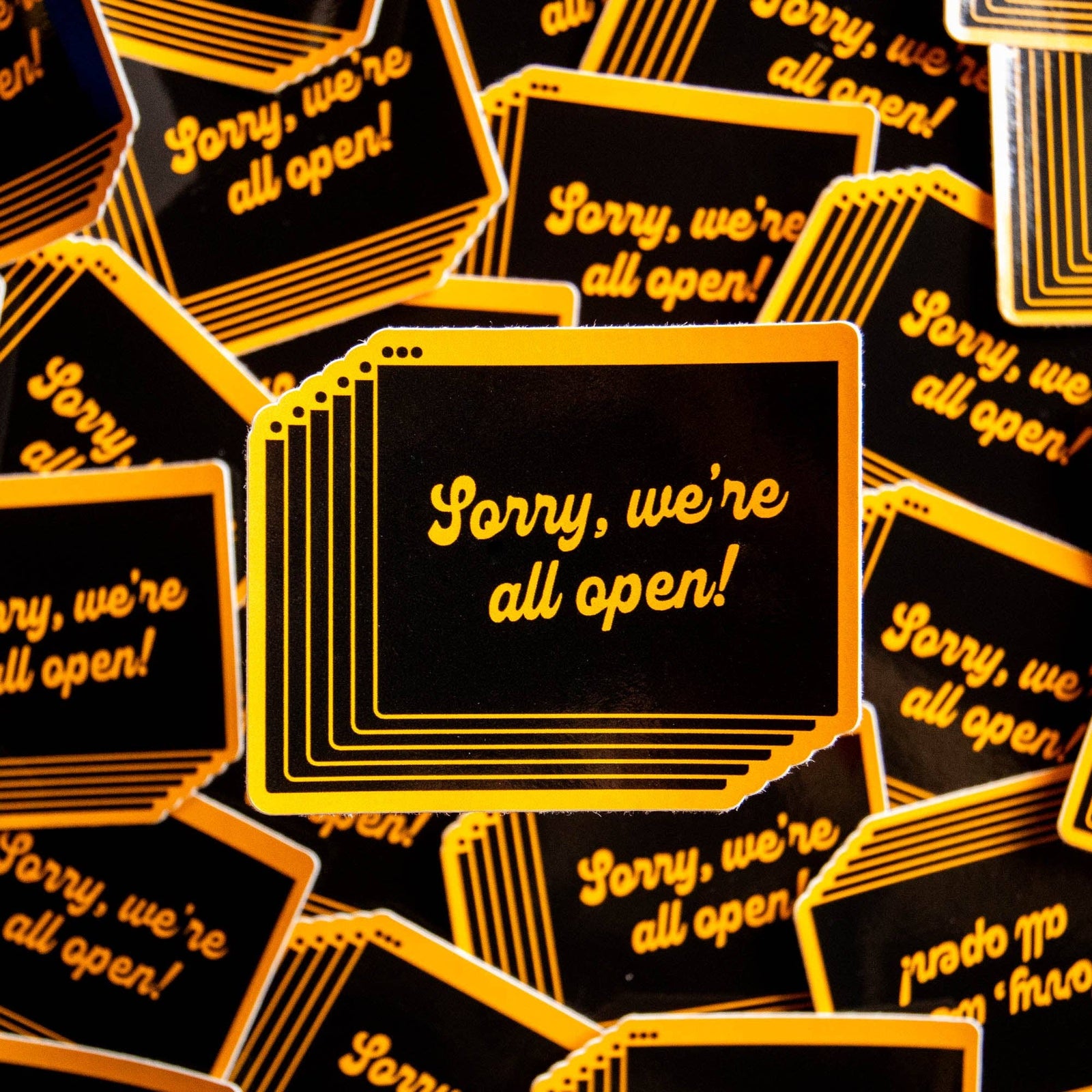 A stack of stickers featuring lots of open browser tabs with 'Sorry, we're all open!' text in yellow on a black background.