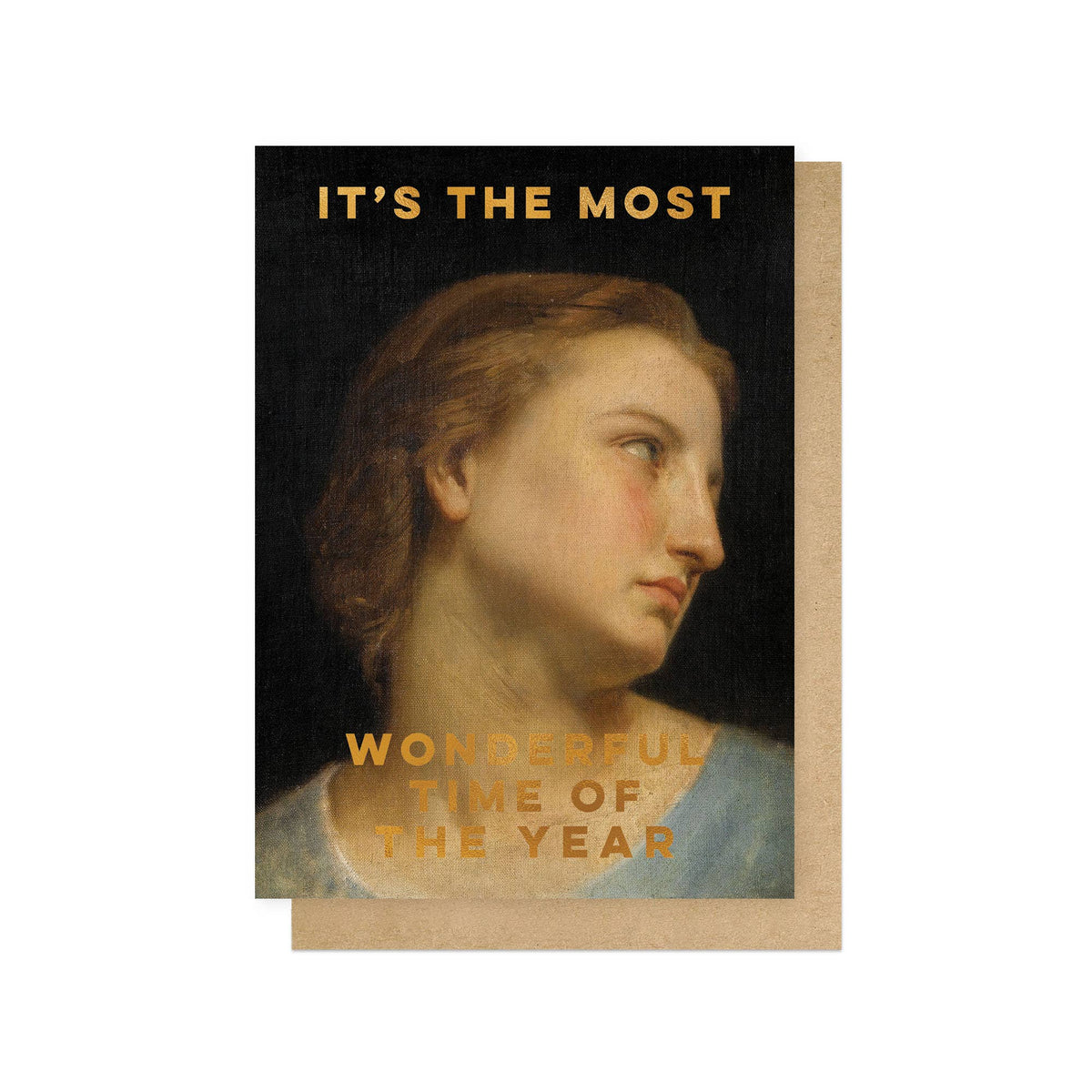 A Christmas card featuring a classical painting-style portrait of a woman in profile on a dark background, with gold text reading 'IT'S THE MOST' at the top and 'WONDERFUL TIME OF THE YEAR' at the bottom. A kraft paper envelope is placed behind the card on a white background.