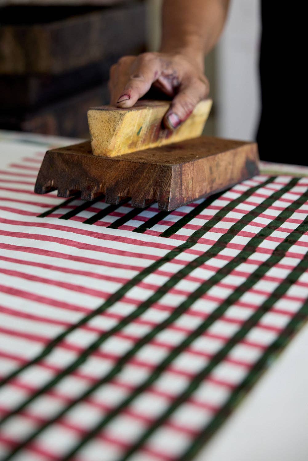 person printing onto wrapping paper with a wooden block.