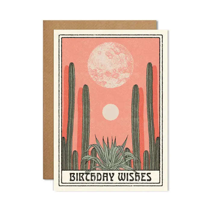 A greetings card with a black frame around the side and an image of a pink moonrise/sunset in the background and green cacti in the foreground. The words &#39;birthday wishes&#39; feature in black at the bottom.