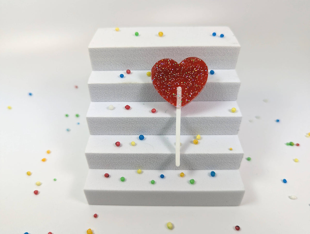 Red Heart Lollipop Glitter Brooch by penny black showing on a stair out of box