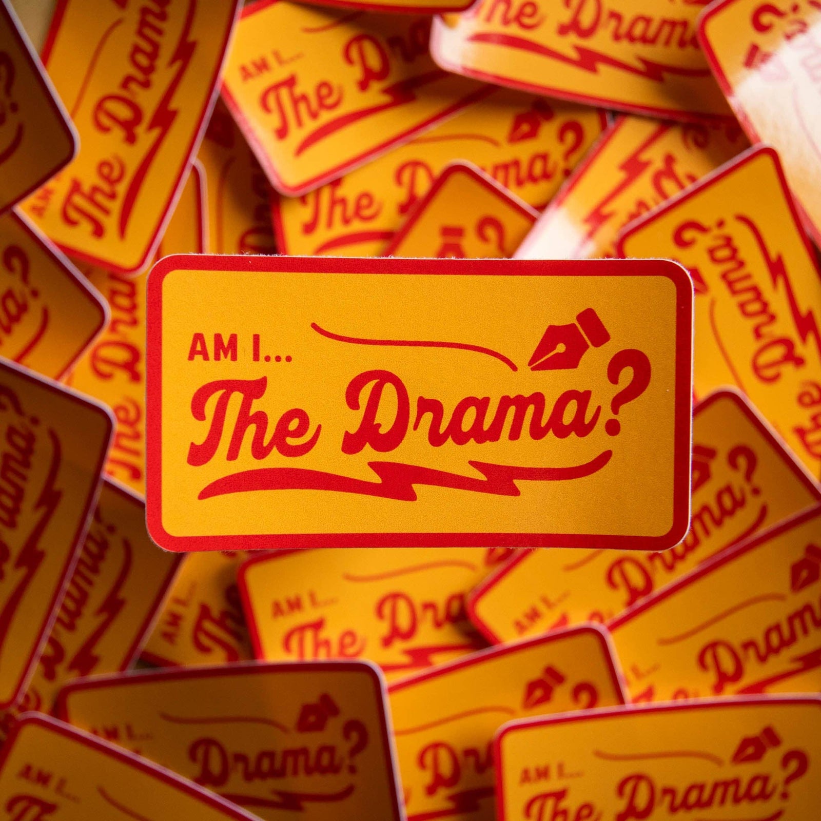 Pile of mustard stickers with 'AM I... The Drama?' in red text with a fountain nib icon on.