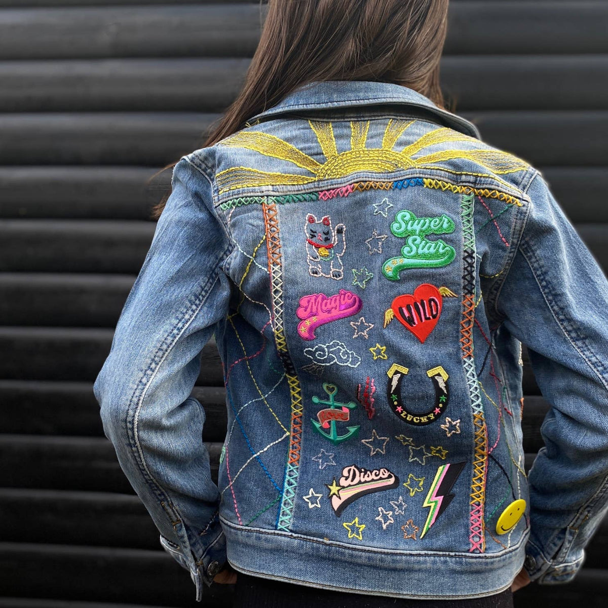 Colourful Iron on Patch - pink budgie by penny black showing back of denim jacket with lots of patches