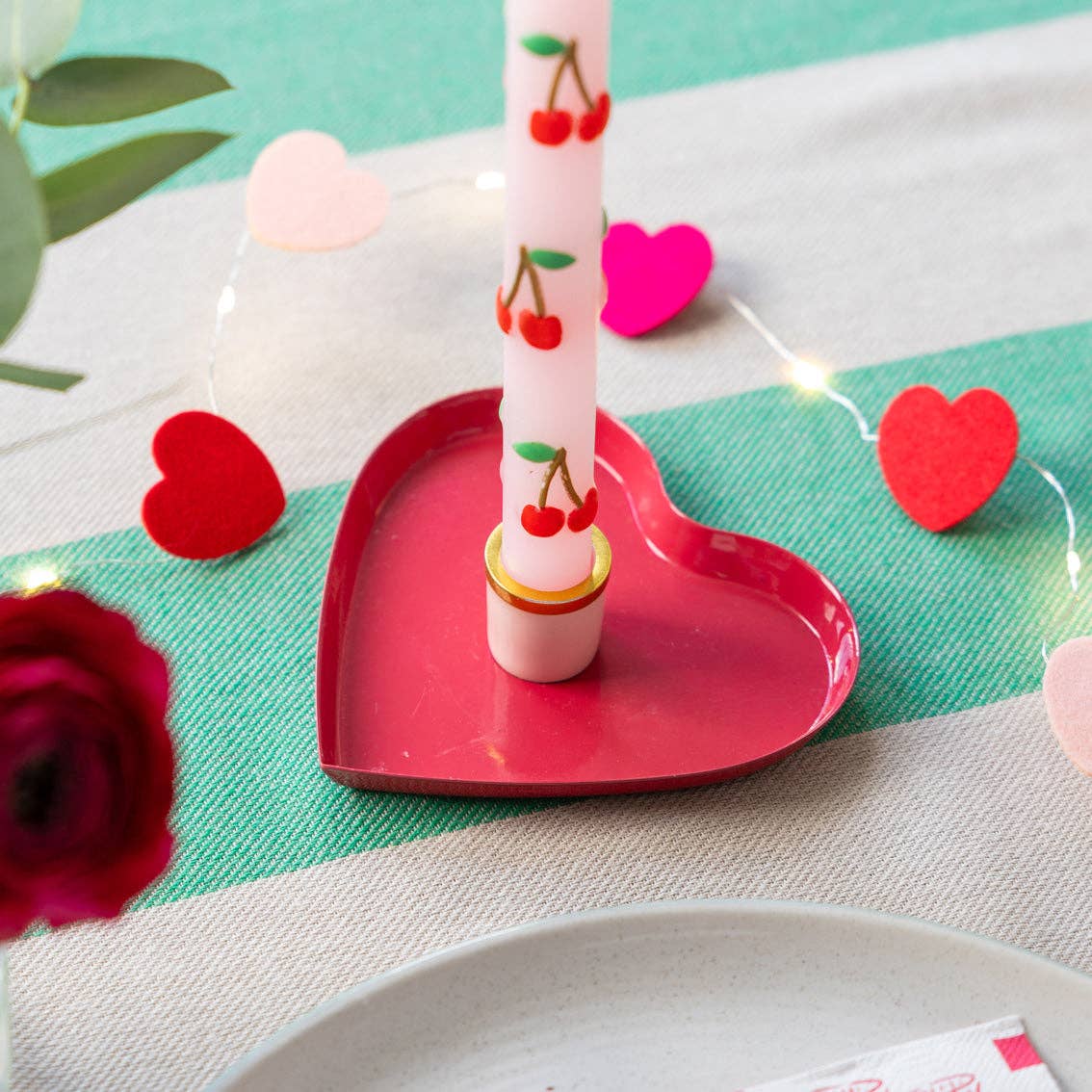 Heart Shaped Enamel Candle Holder with cherry decorated dinner candle on a tabletop by penny black