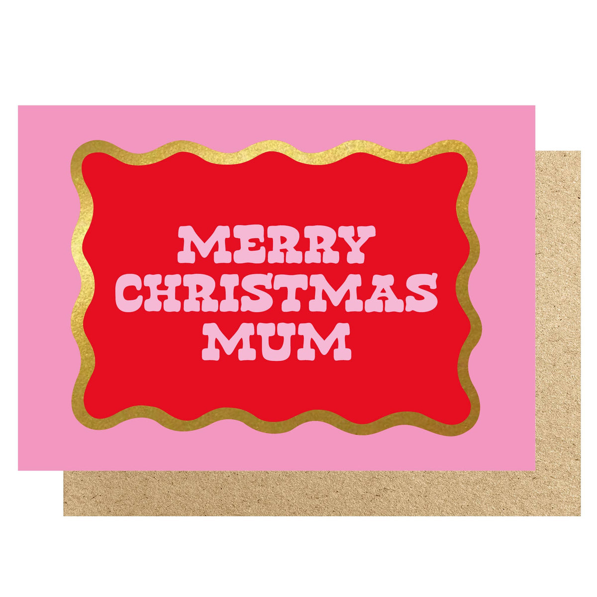 A Christmas greeting card with a bright pink background, a large red central label outlined in gold foil, and the words “MERRY CHRISTMAS MUM” in white. A kraft paper envelope is partially visible underneath on a white background.
