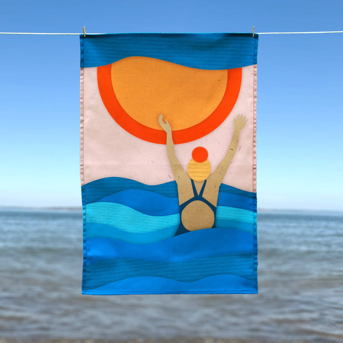 Sea & Wave Collage Wild Swimming Tea Towel shown on a washing line by penny black