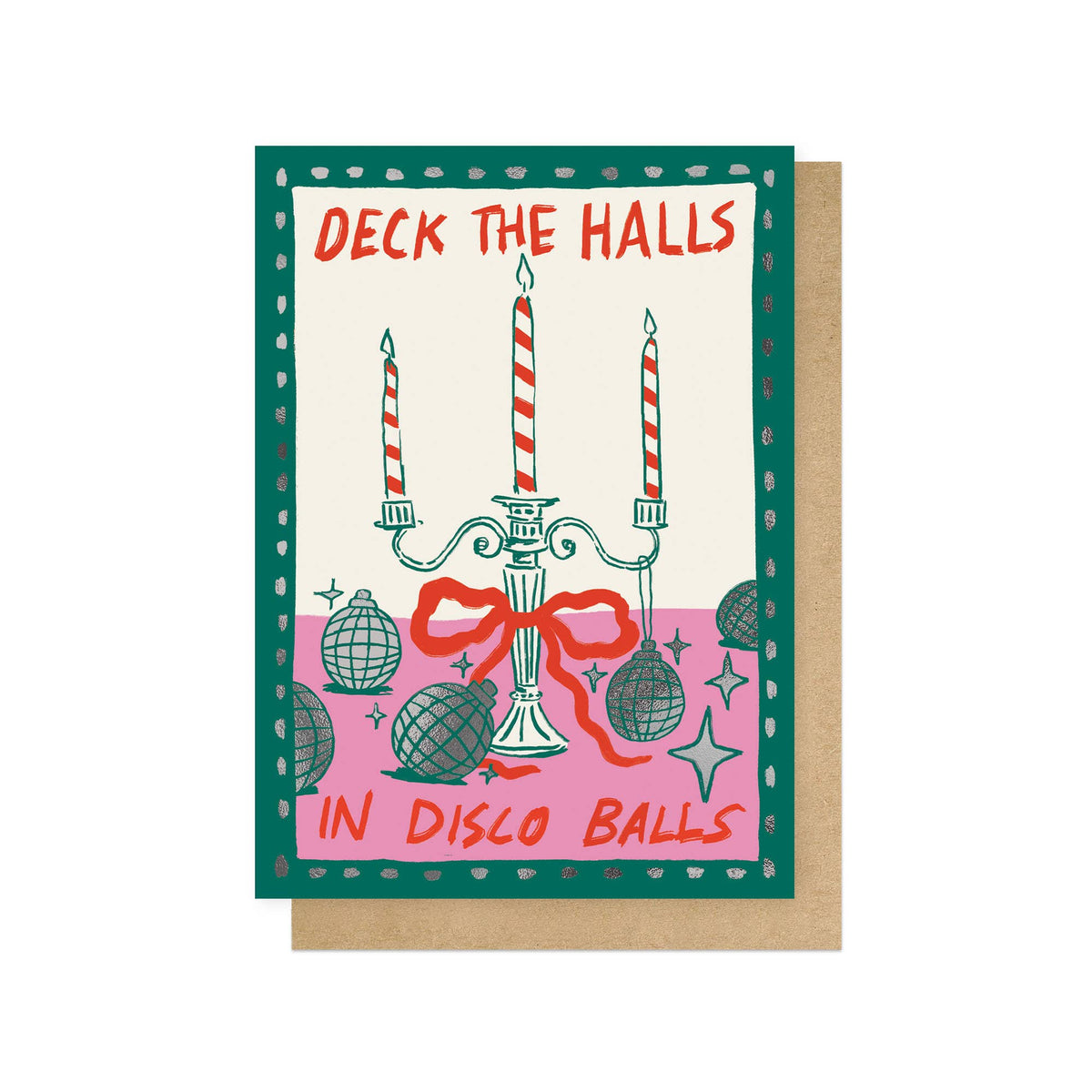 A christmas greeting card with a festive illustrated design featuring a candelabra, disco balls, stars, and the text 'DECK THE HALLS IN DISCO BALLS' on a cream background, with a green border. A kraft paper envelope is partially visible behind it on a white background.