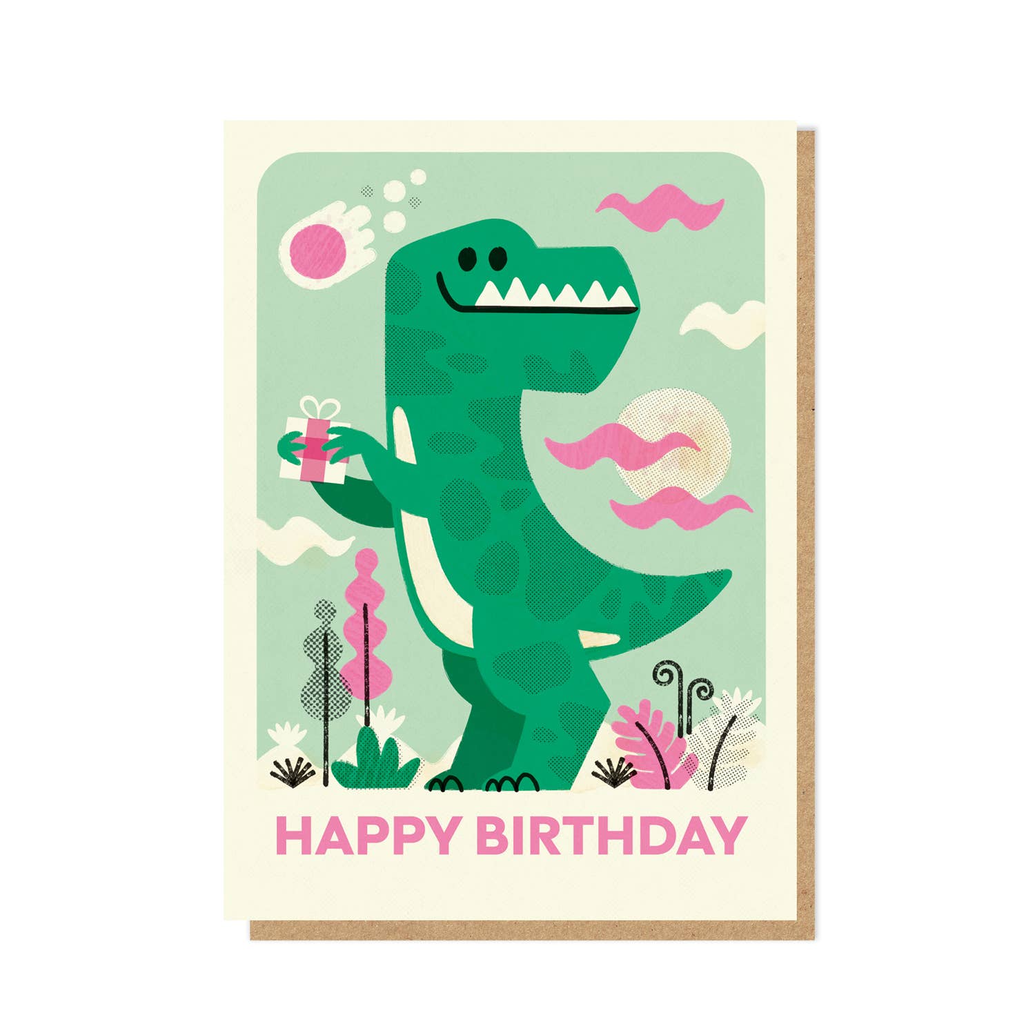 A birthday card featuring an illustrated green dinosaur holding a pink gift box, with the words “HAPPY BIRTHDAY” in pink at the bottom. The card has an off-white border and is shown with a kraft envelope behind it on a light gray background.