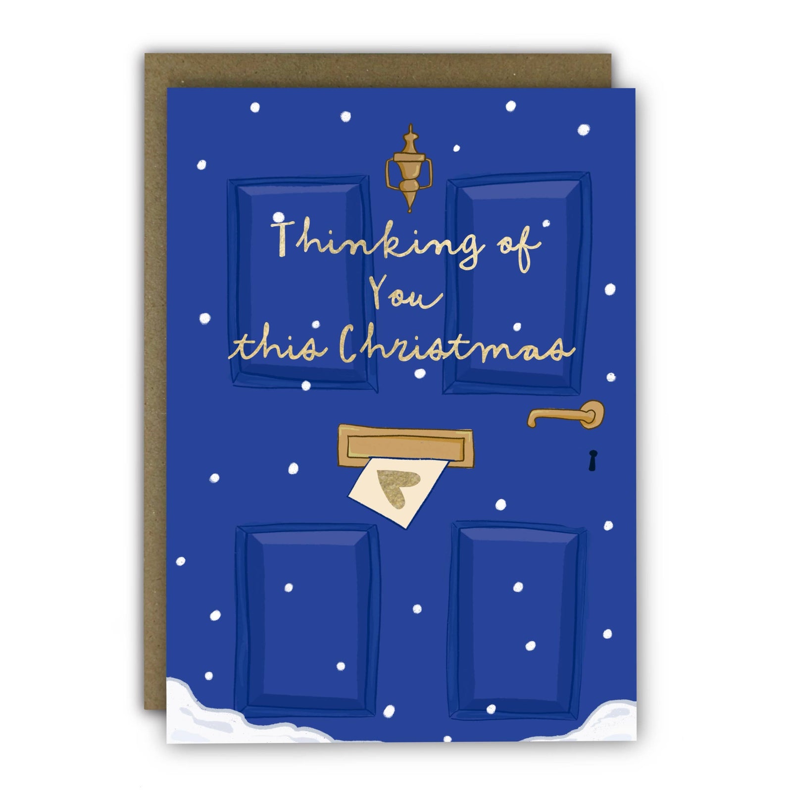 A Christmas greeting card featuring an illustrated blue door with snow, gold text reading 'Thinking of You this Christmas,' and a gold-toned letterbox and handle, shown with a brown envelope behind it on a white background at penny black