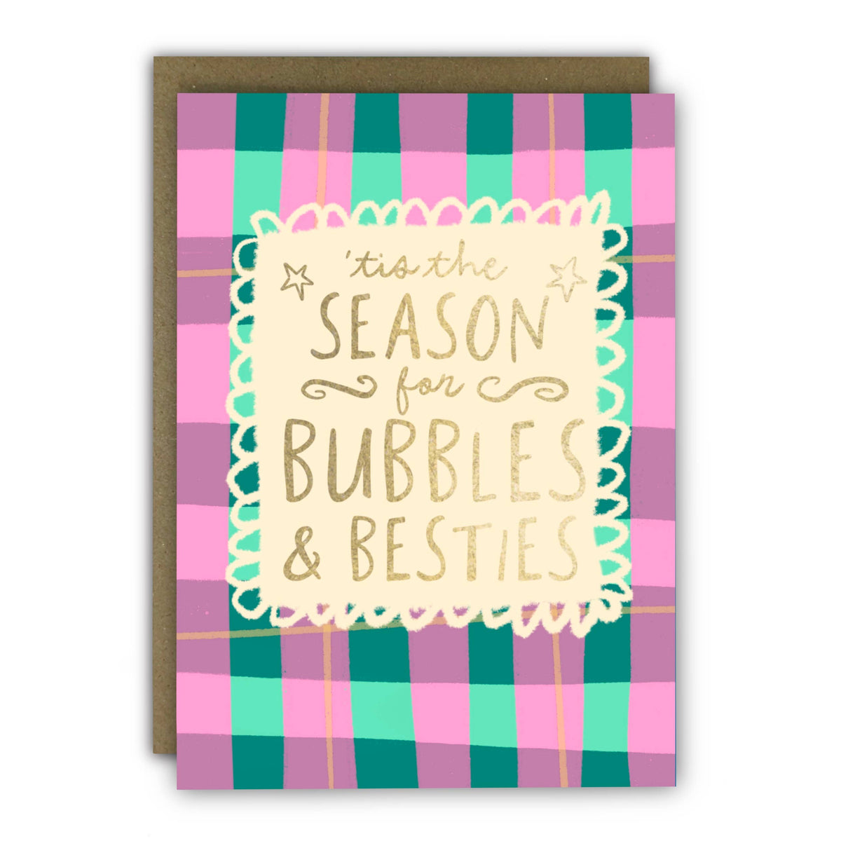 A Christmas greeting card with a pink, teal, and purple plaid pattern and a central cream label that reads “tis the SEASON for BUBBLES & BESTIES” in gold lettering. A brown envelope is behind the card at penny black