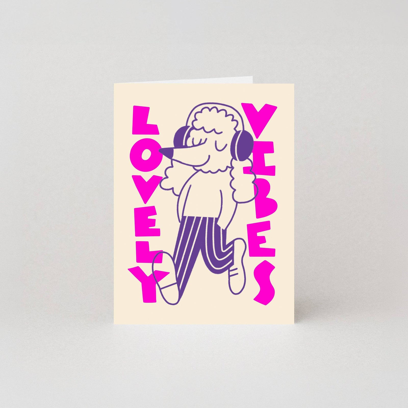 Greeting card with a dog character wearing headphones and text 'LOVELY VIBES' in neon magenta ink on a cream background
