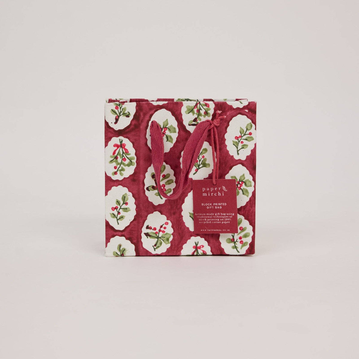 A small Christmas gift bag with a festive foliage pattern on a light gray background by paper mirchi at penny black