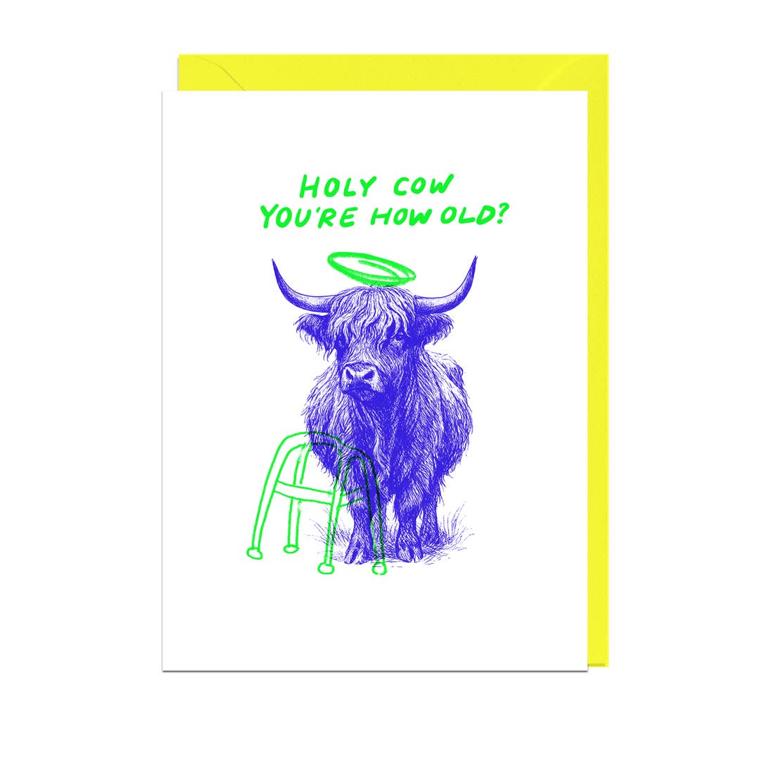 Greeting card with a blue highland cow illustration and text 'Holy Cow You're How Old?' on a white background with yellow envelope.