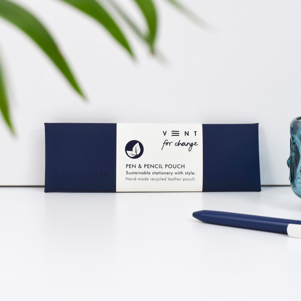 A navy blue pen and pencil pouch made of recycled leather and has the word &#39;Reclaim&#39; embossed in it.