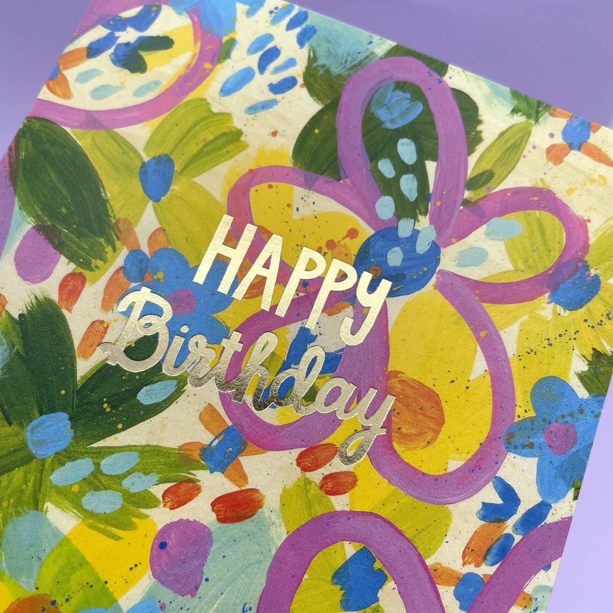 A colourful abstract painted floral greetings card to celebrate a birthday. The writing in the centre of the card is gold foil cursive writing stating &#39;Happy Birthday&#39;.