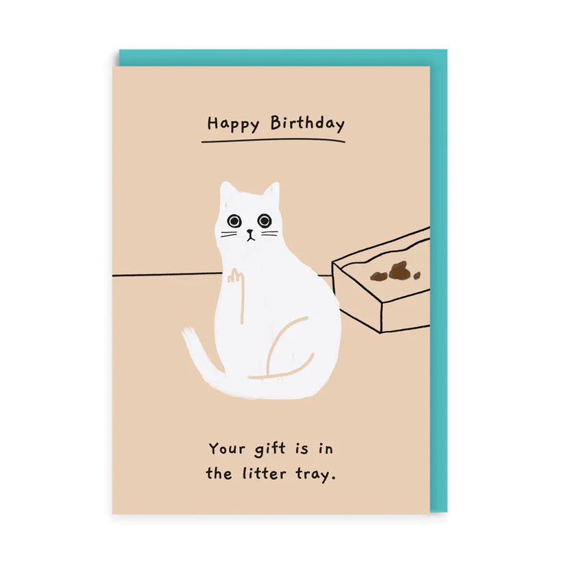 A beige greetings card with a white illustration of a cat putting up the middle finger wiht an outline of a litter tray behind it and some cat poo in it. The words &#39;Happy Birthday&#39; are handwritten and underlined above the cat and below it says, &#39;your gift is in the litter tray&#39;.