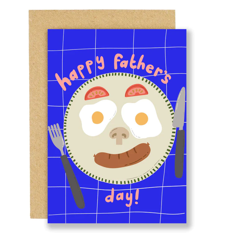 A greetings card with a royal blue background and illustration of a plate and cutlery. There is a breakfast fry up on the plate with tomato wedges for eyebrows, fried eggs for eyes, a sliced mushroom for a nose and a sausage for a smile. The words 'Happy Father's Day!' also feature.