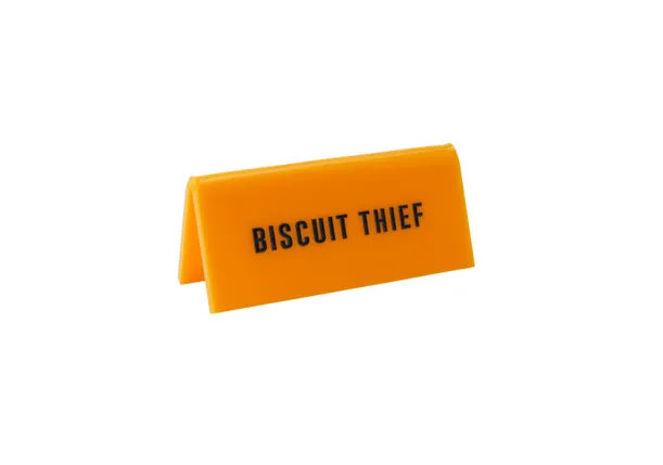 A small yellow acrylic sign that has in big black capital letters on it &#39;BISCUIT THIEF&#39;.