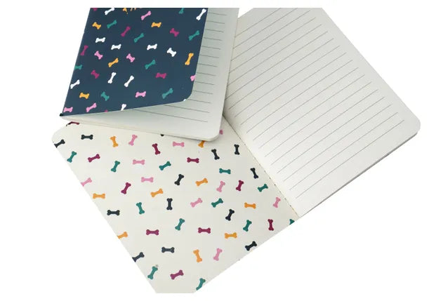 An image of inside a notebook set. The covers show lots of colourful dog bones and the writing pages are ruled.