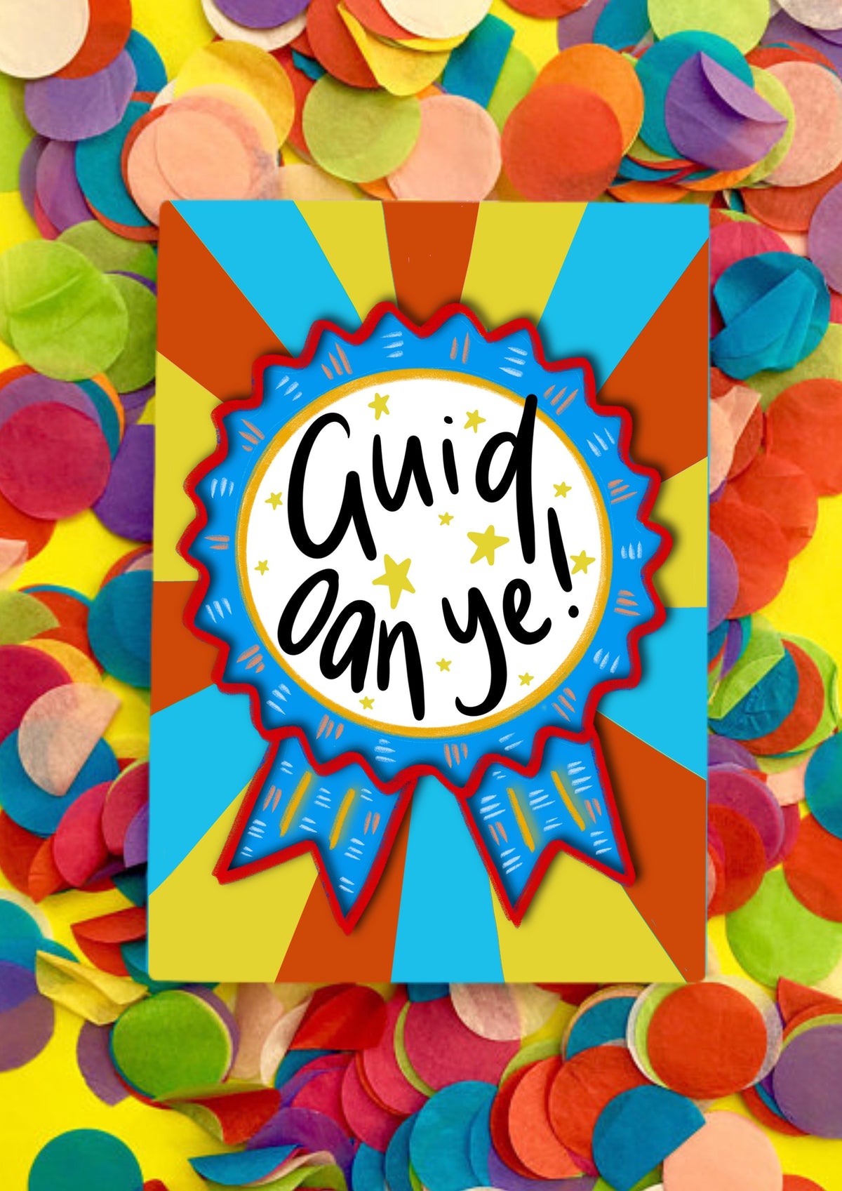 A greetings card with a stripey sunbeam designed background with a large rosette motif. The rosette is royal blue with red edging and has a large white circle in the middle that has the words handwritten &#39;guid oan ye&#39;. The card is lying on a bed of rainbow confetti.