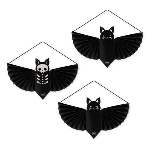 Three black bat-shaped hanging decorations with pleated wings are arranged on a white background. Two feature a white skeleton design on the bat body, and one features a black cat face with pink cheeks and small red eyes.