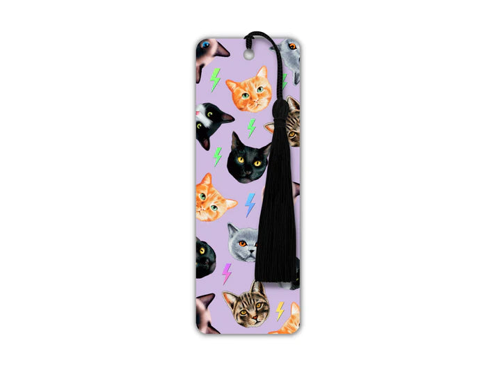 A long rectangular shaped bookmark with long black tassel. The design on the bookmark has a lilac background and is covered in cutout cat heads of different types of cats - tabby, ginger, black and white, grey.