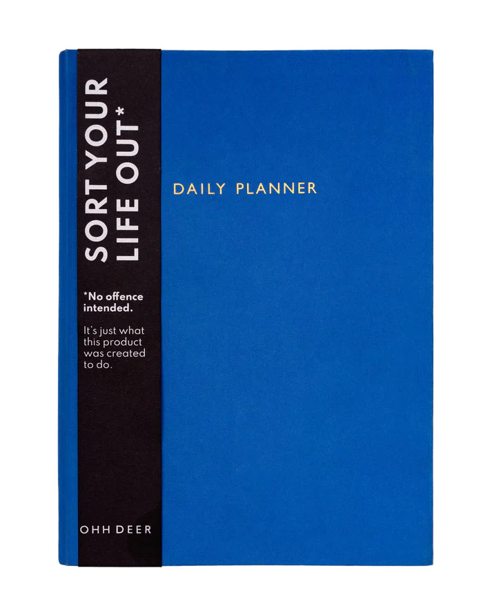 The front cover of a daily planner by Ohh Deer. The cover design is a bright and warm royal blue colour. There are gold embellished words saying in capitals &#39;DAILY PLANNER&#39;. The image shows a black belly band including details about the product.