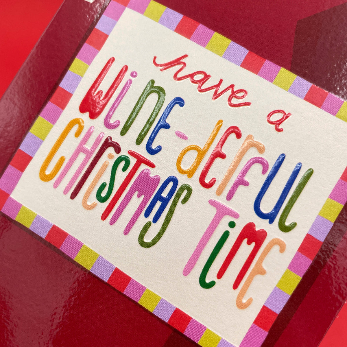 A close up on A christmas card in the shape of a red wine bottle featuring a label with the words &#39; have a wine-derful christmas time&#39;.