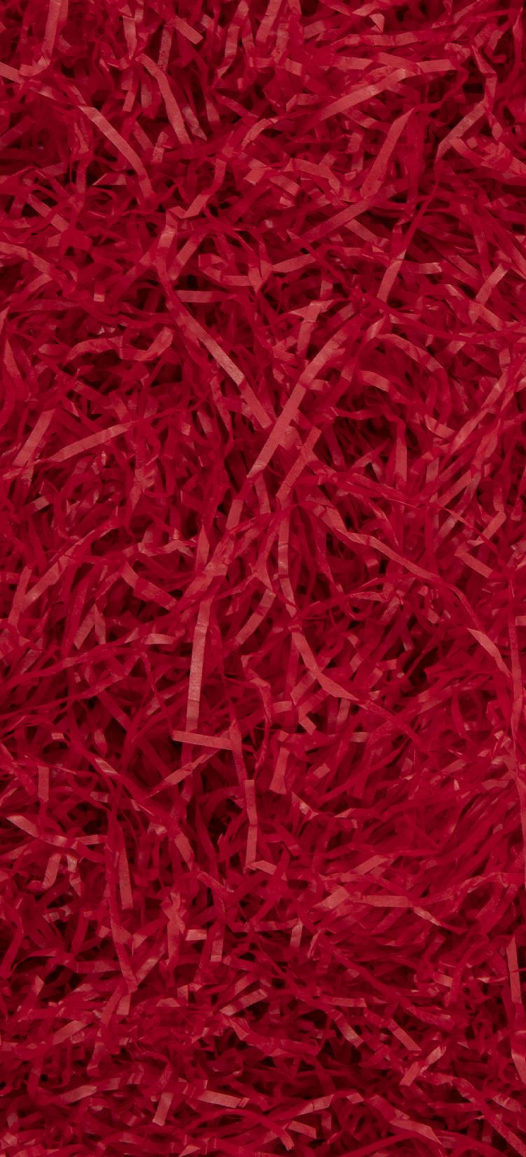 A close-up texture shot of bright red shredded paper filling the entire frame.