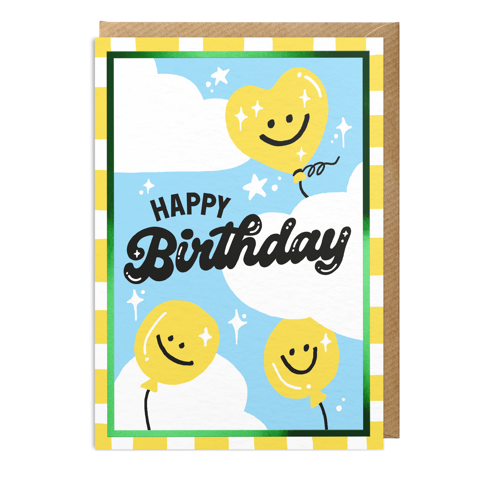 An A6 birthday card with a brown envelope behind it, featuring a light blue sky, white clouds, and three yellow smiley-face balloons. The card has a checkered border and the words “HAPPY Birthday” in black script.