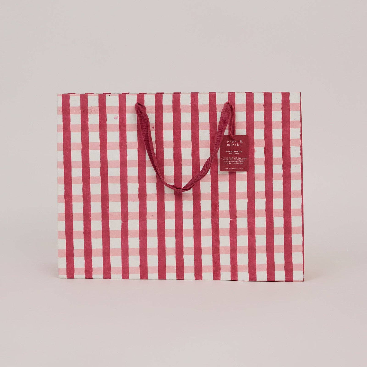 A large christmas gift bag with pink plaid design on a light gray background by paper mirchi at penny black