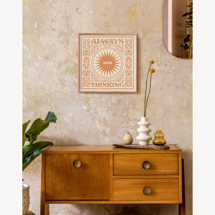 An orange and cream graphic art print shown on a living room wall.