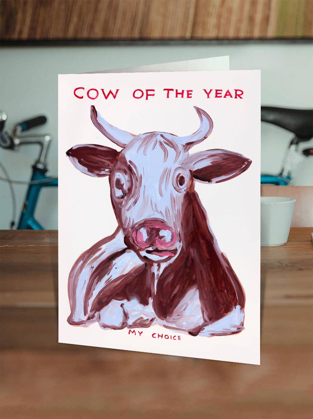 Cow Of The Year David Shrigley Funny Card by penny black shown on a tabletop