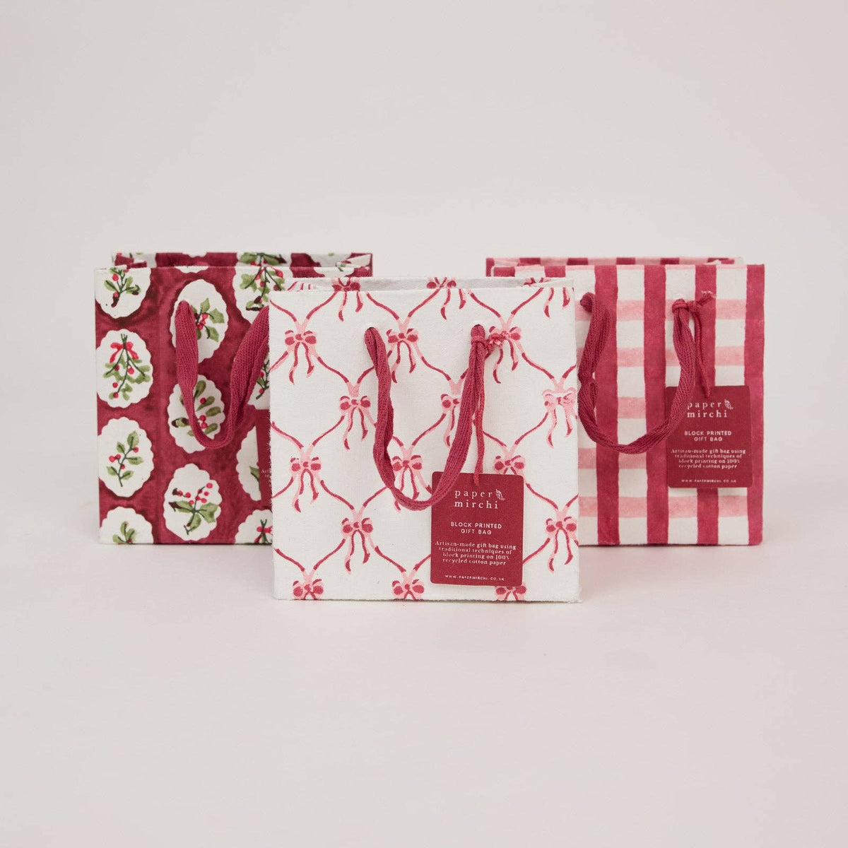Three pink and red colour decorative small gift bags with different patterns on a light gray background by paper mirchi at penny black