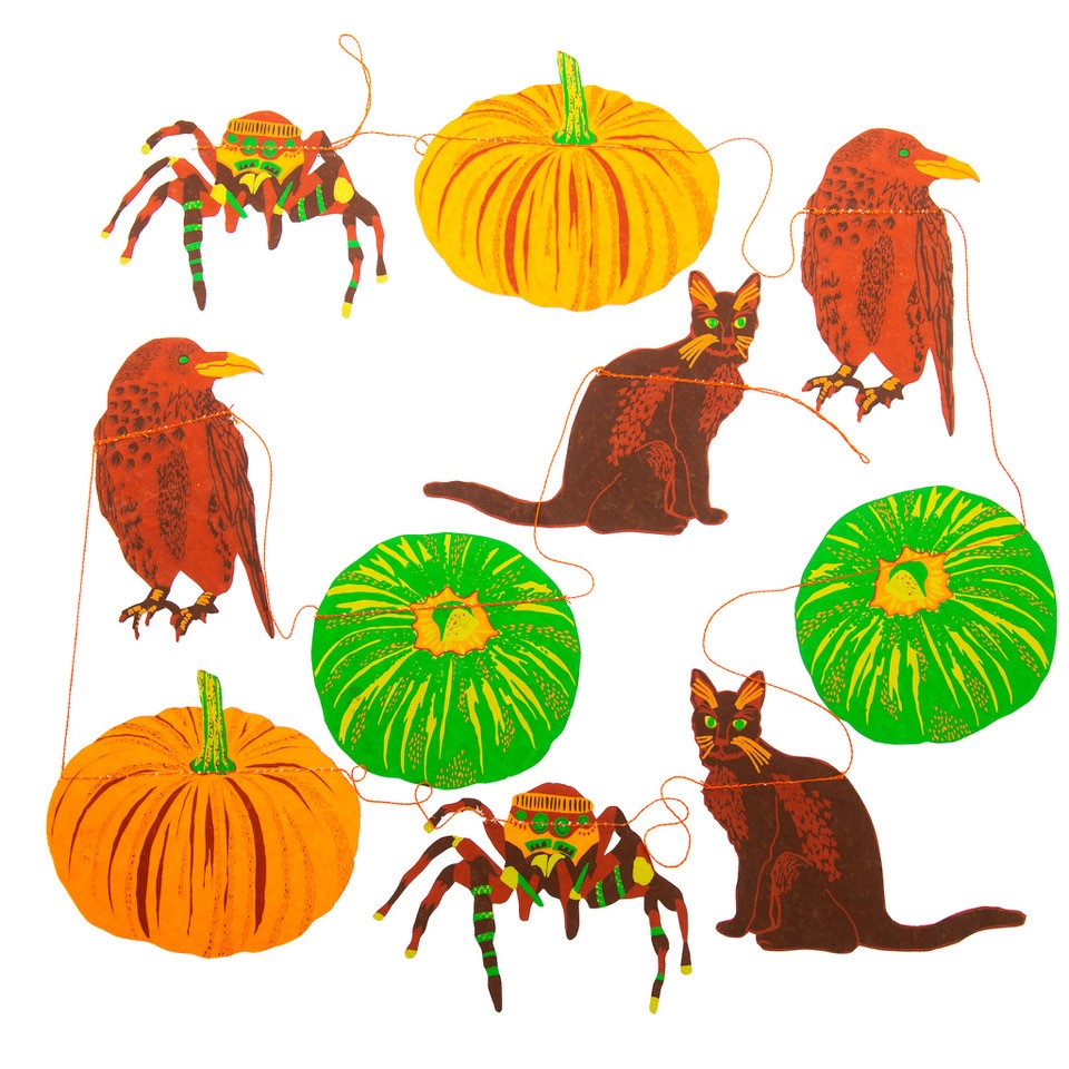 A halloween garland featuring a spider, pumpkins, cats and ravens on a thin thread. They are various colours of screen print - lime green, orange, brown and dark reds.
