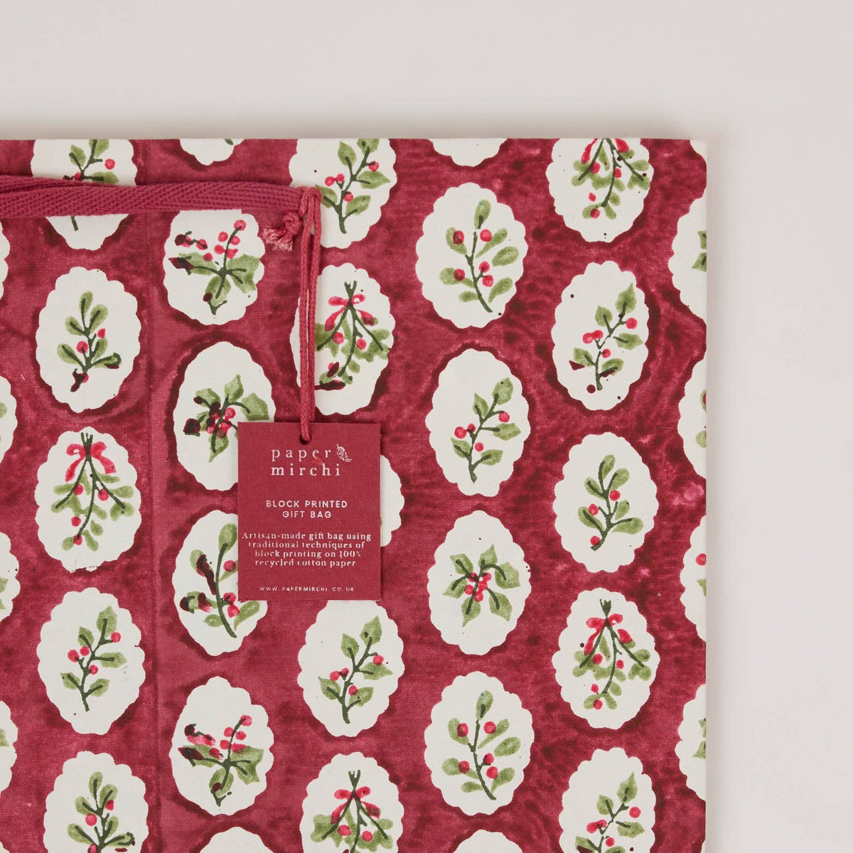 Close up on a large christmas gift bag with scalloped foliage design on a light gray background by paper mirchi at penny black