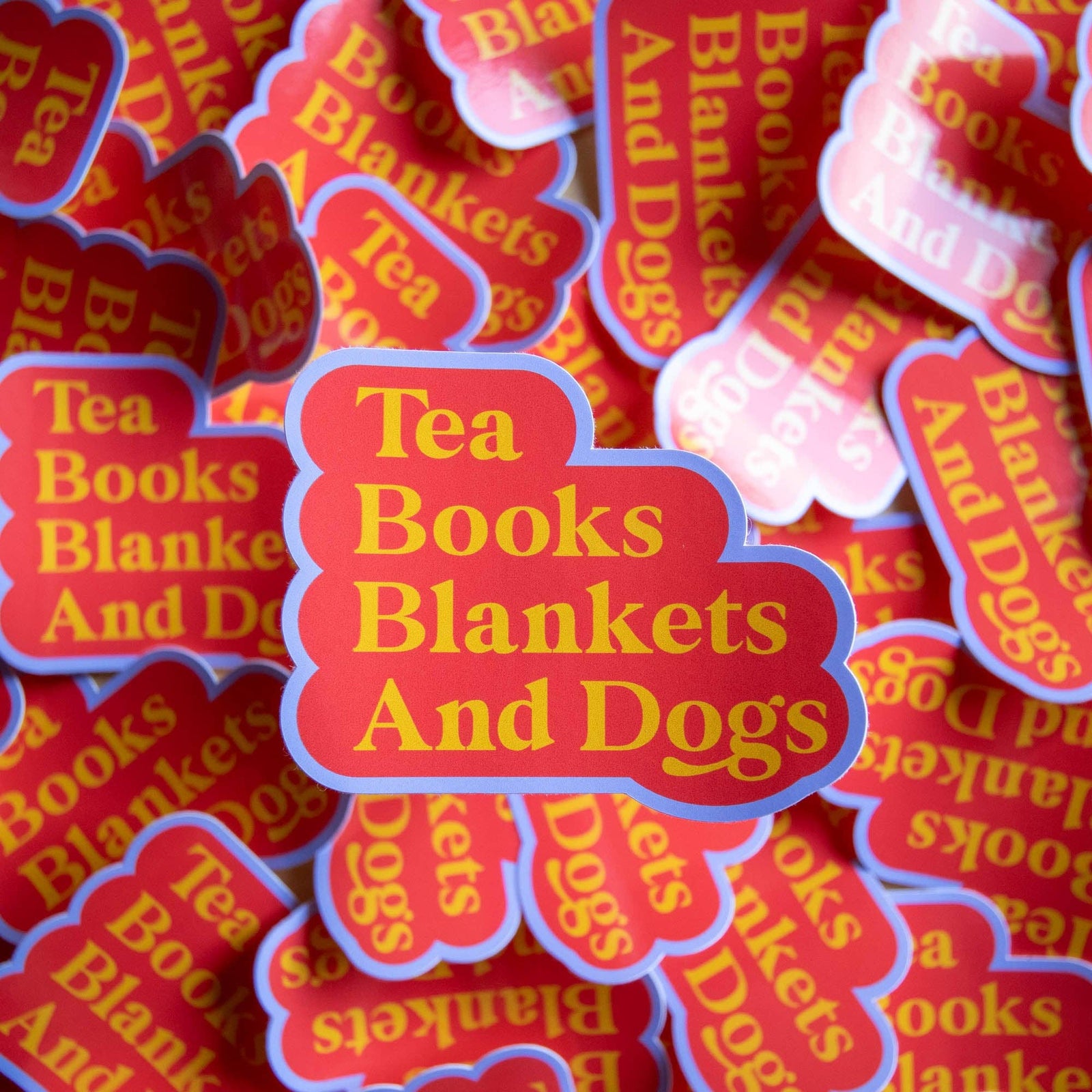 Stack of 'Tea Books Blankets And Dogs' stickers with red and yellow text.
