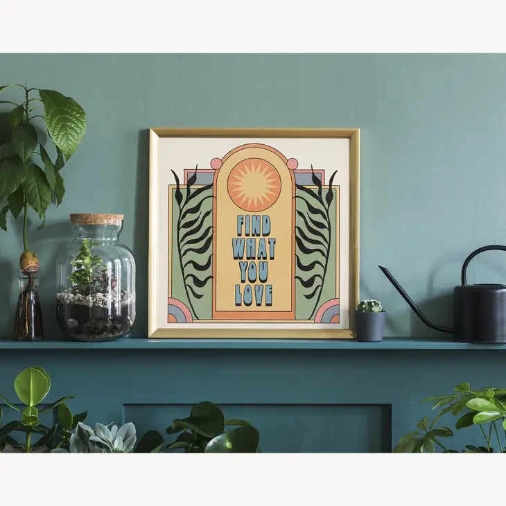 A colourful graphic art print shown on a shelf in a house against a teal wall.