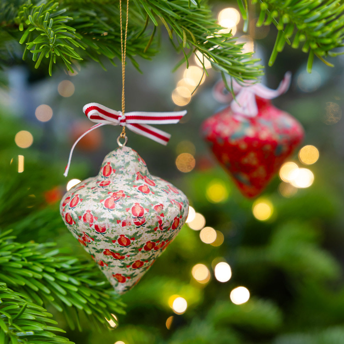 Decorative Christmas ornaments hanging on a tree with blurred lights in the background