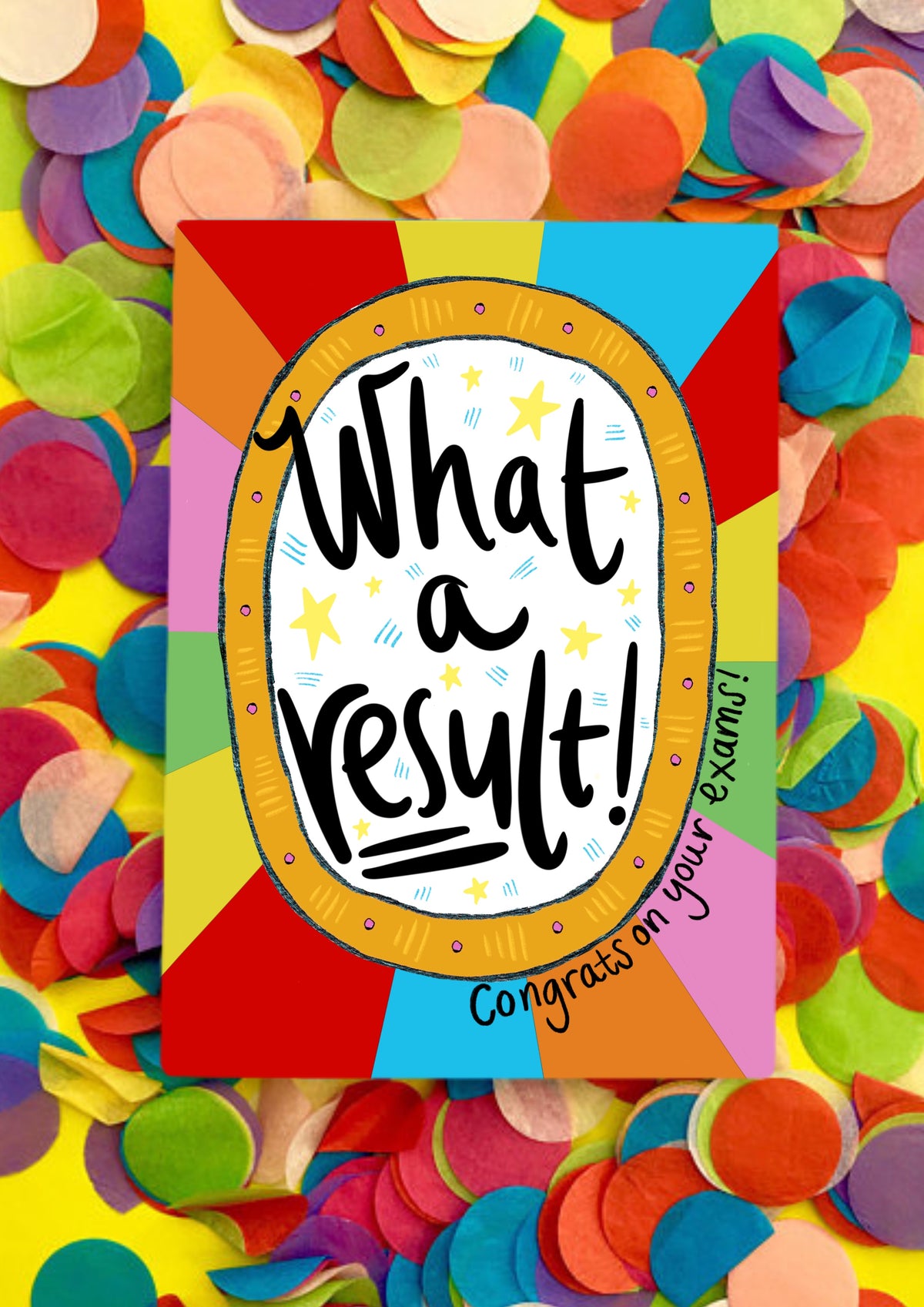 A greetings card with a rainbow sunbeam designed background with a large white circle motif in the middle that has the words handwritten &#39;what a result!&#39;. Around the bottom right of the central motif are the words &#39;congrats on your exams&#39;. The card is lying on a bed of rainbow confetti.