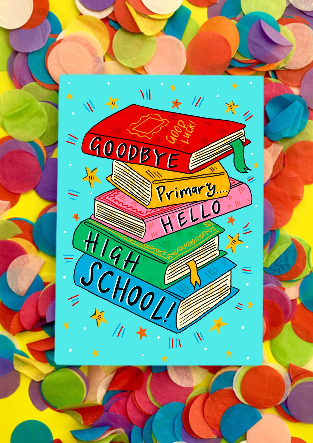 A greetings card with a white background covered in light blue squares like a jotter. The main image is a colourful jauntily stacked textbooks with the words &#39;Goodbye primary... hello high school!&#39; - one word on each book. The card is lying on a bed of rainbow confetti.