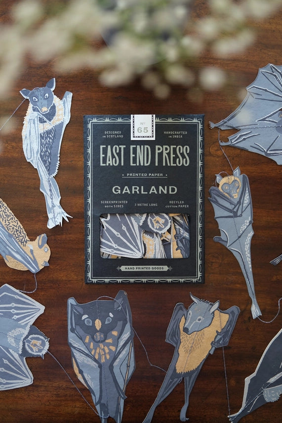 An image of a paper garland of bats, some in the packaging and some on a table top.